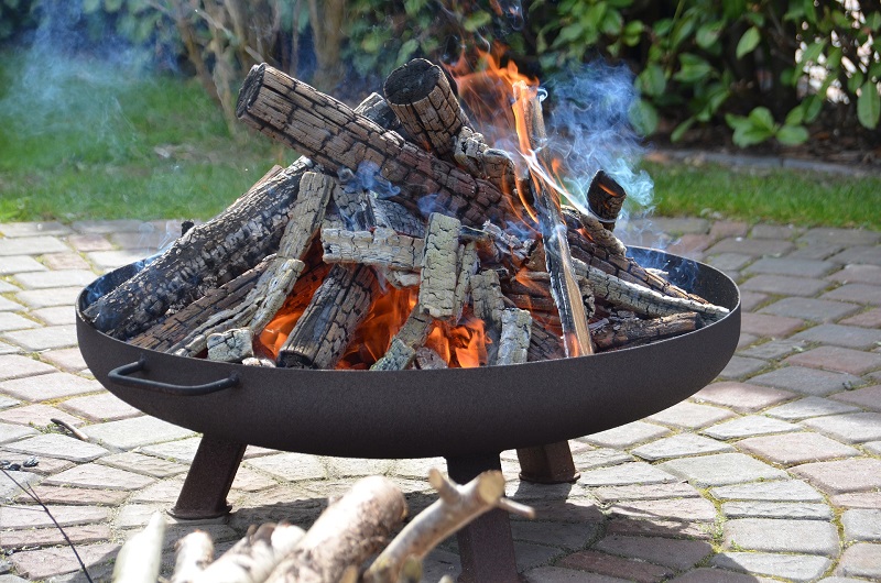 Eine Feuerschale mit angebranntem Holz und Asche Brennende Feuerschale mit angebranntem Holz
