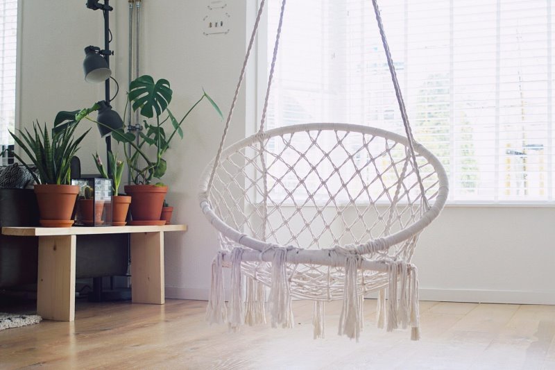 Makramee Hängesessel hängend in einem Wohnzimmer Makramee Hängesessel hängend in einem Wohnzimmer